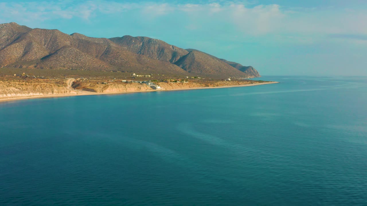 Aerial coastline with ocean foreground and mountain slopes in the background