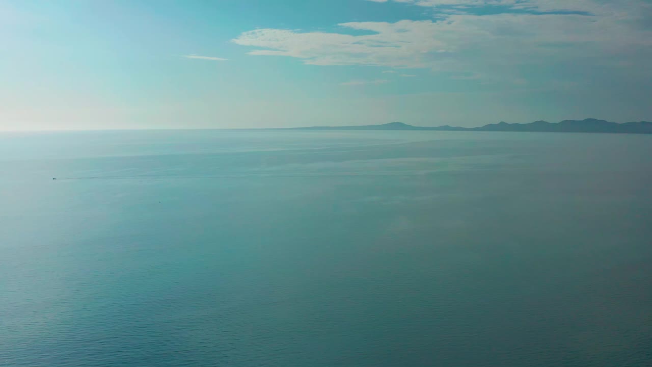 Second frame of the El Sargento La Ventana ocean view, with the sea filling the frame, a small dark speck on the water, distant landforms to the right, and no visible people.