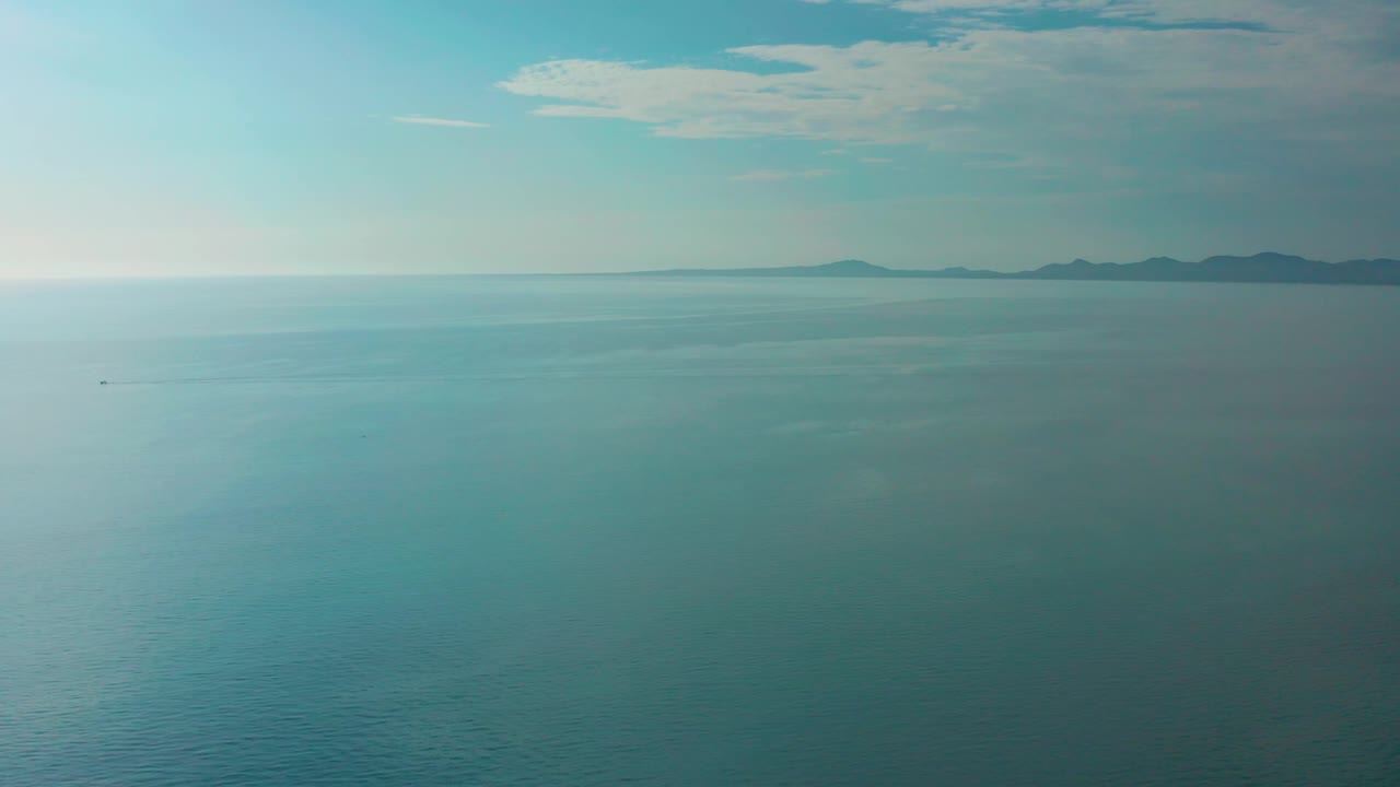 Third frame shows open water at El Sargento La Ventana, Mexico, with muted turquoise color, low distant mountains along the right horizon, high thin clouds, and no visible people.