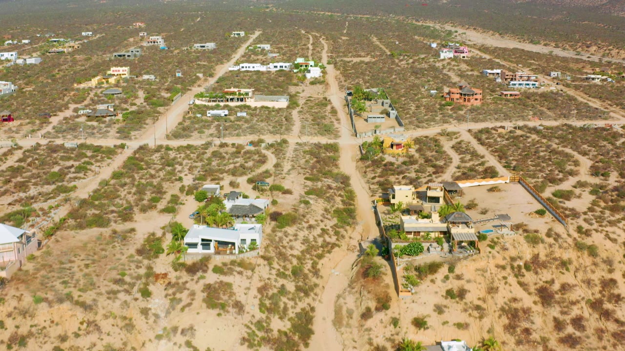 Drone view of desert lots and houses near low hills