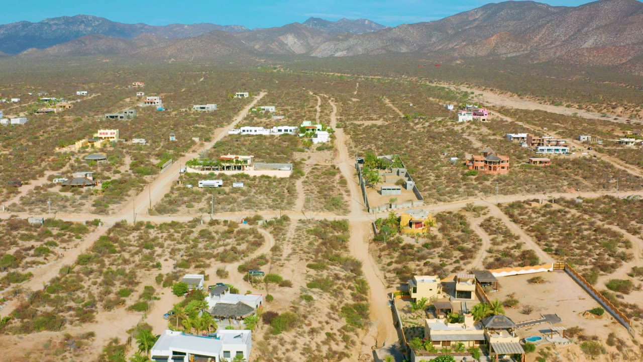 Wide aerial desert community with roads, lots, and distant mountains.