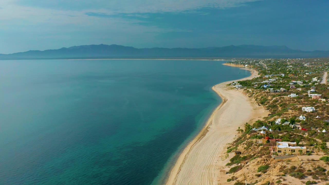 Aerial view of bay water and sandy shoreline with small coastal settlement