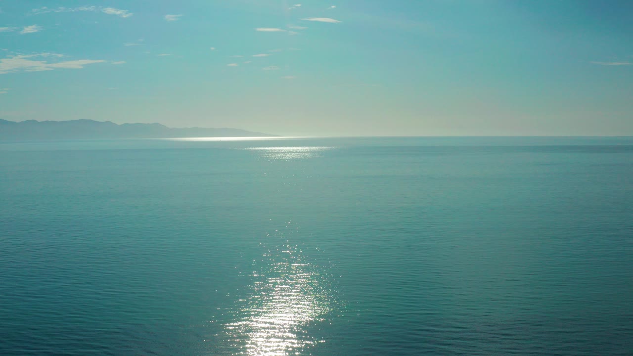 Wide blue ocean with sun reflection and distant horizon