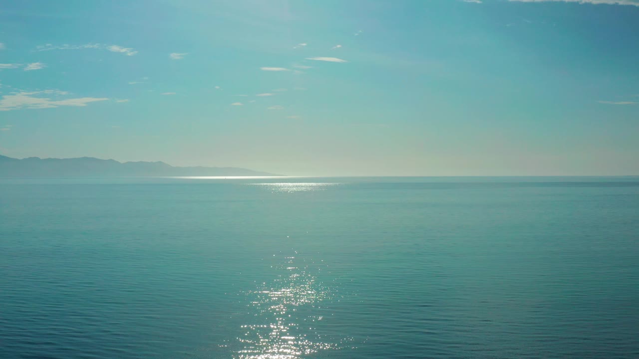 Blue-green ocean near El Sargento La Ventana, Mexico, with low sun glare near the horizon, rippled water below, and no visible people.