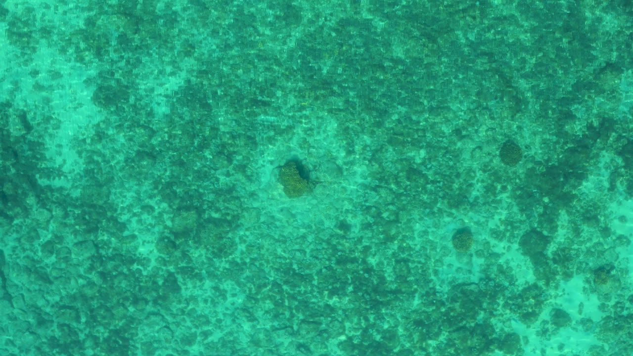 Aquamarine sea surface in El Sargento La Ventana, Mexico, shows darker underwater blotches and faint ripple lines, with no shoreline, boats, or visible people.