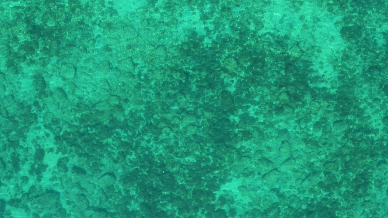 Clear turquoise ocean in El Sargento La Ventana, Mexico, seen from above with darker seabed marks and no visible people, boats, or shoreline.