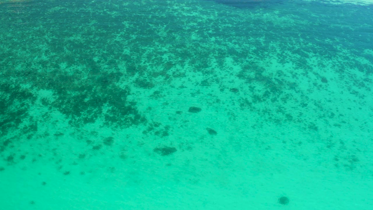 Opening frame of turquoise shallow water in El Sargento La Ventana, Mexico, with darker seabed patches across the upper half and no visible people.