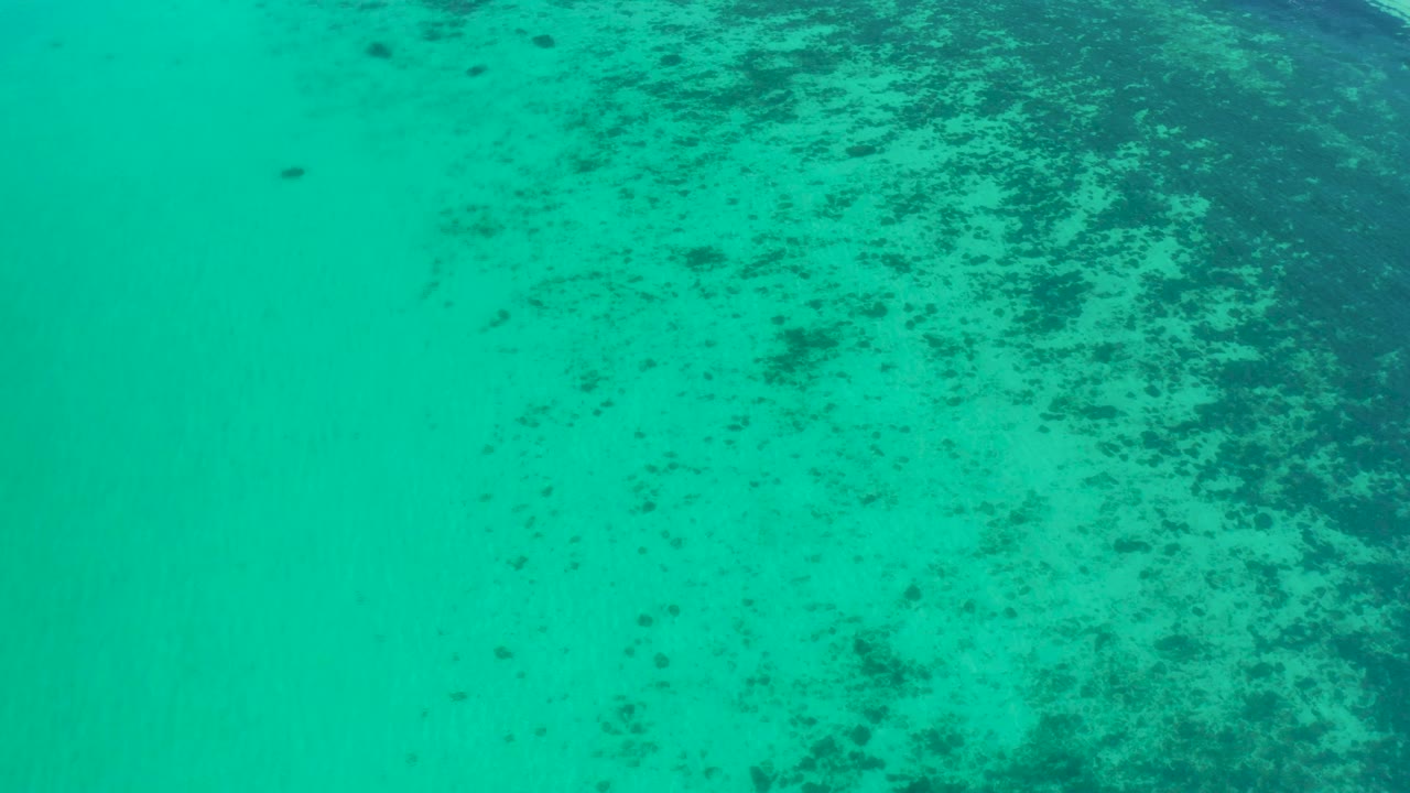 Turquoise ocean seen from above near El Sargento La Ventana, Mexico, with reef mottling heavier on the right side and no visible people.