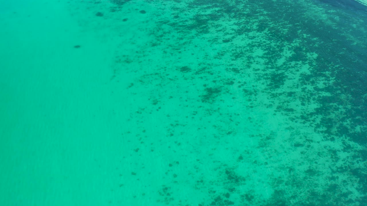 Overhead blue-green water near El Sargento La Ventana, Mexico, with scattered dark reef marks beneath the surface and no visible people.