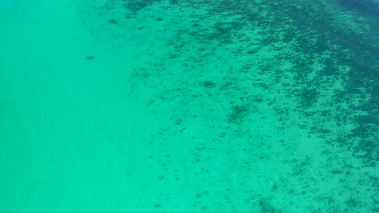 Top-down view of turquoise ocean in El Sargento La Ventana, Mexico, with darker seabed patches concentrated toward the upper right and no visible people.