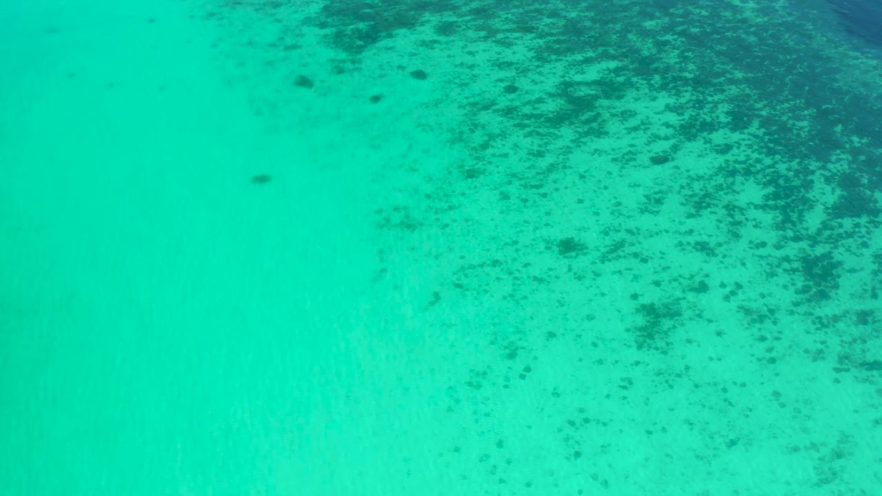 Clear turquoise water fills the frame in El Sargento La Ventana, Mexico, with a denser band of dark underwater texture along the top edge and no visible people.