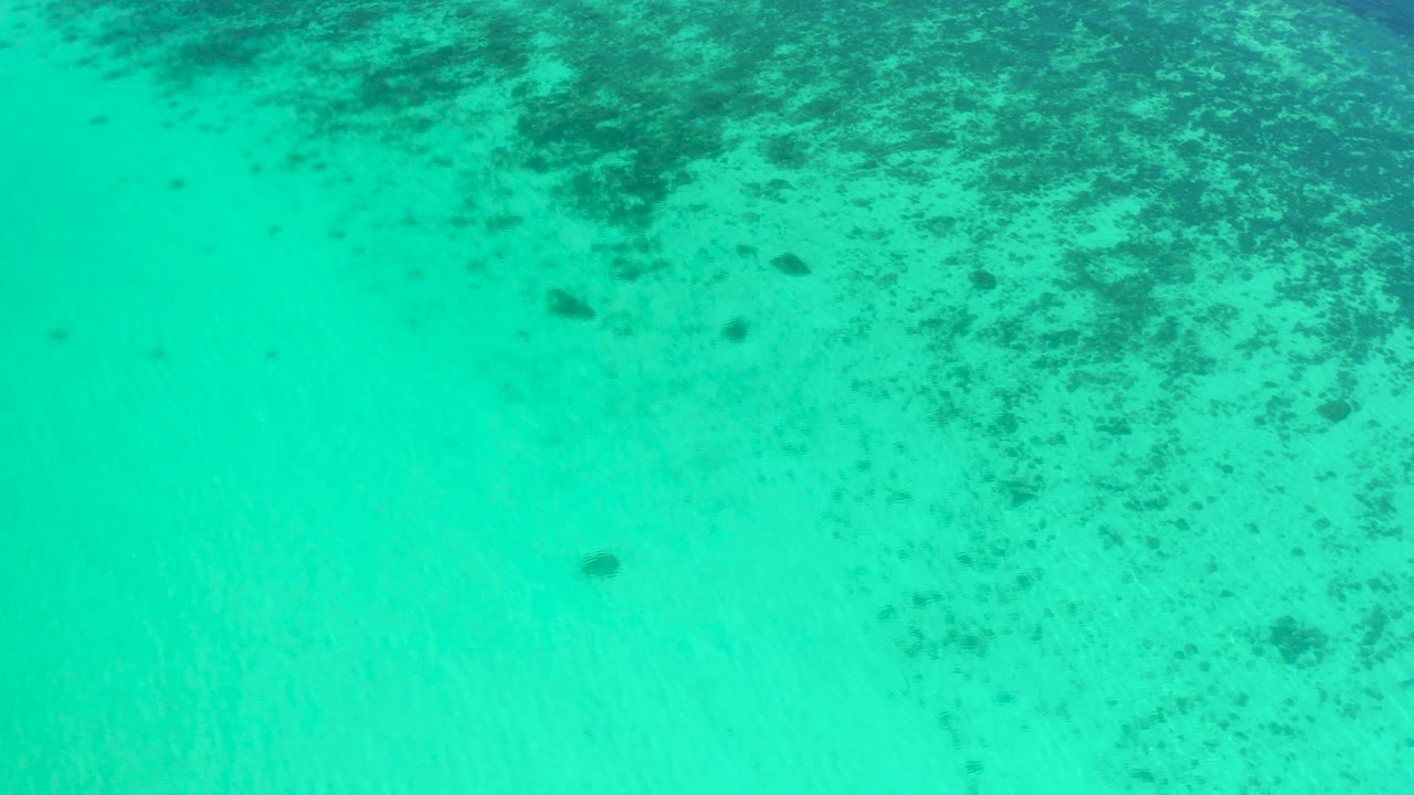 Overhead ocean view with mottled dark patches and clean blue-green water