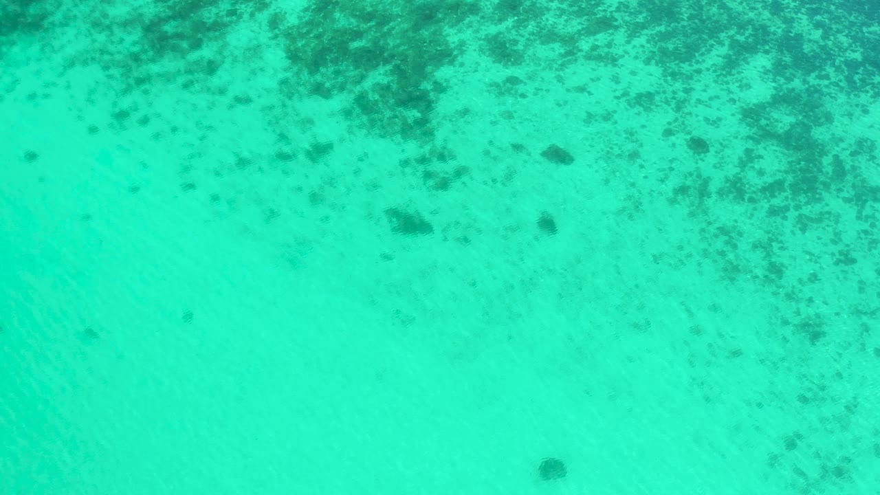 Clear turquoise water in El Sargento La Ventana, Mexico, with a broad pale middle area, darker seabed texture along the top edge, and no visible people.