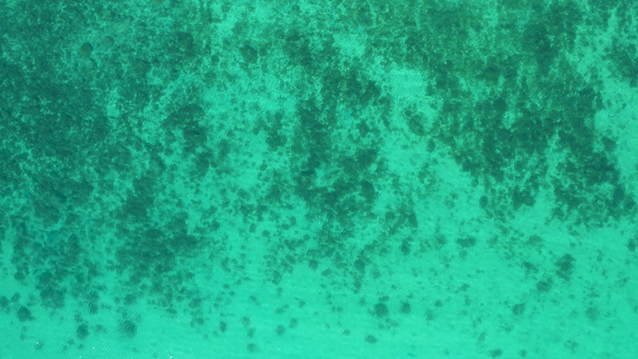 Mottled turquoise water in El Sargento La Ventana, Mexico, with a darker band of underwater texture along the upper frame and no visible people.