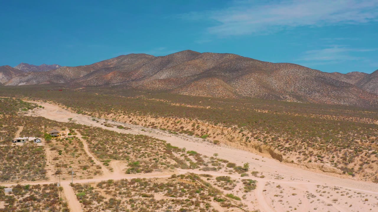 Desert flats, sandy channel, and mountain horizon seen from above.