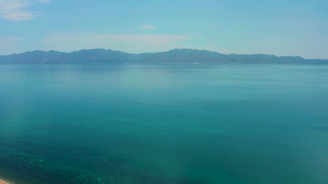 Wide aerial composition over calm water in El Sargento La Ventana, Mexico, with the mountain horizon shifted across the upper frame and no visible people or structures.