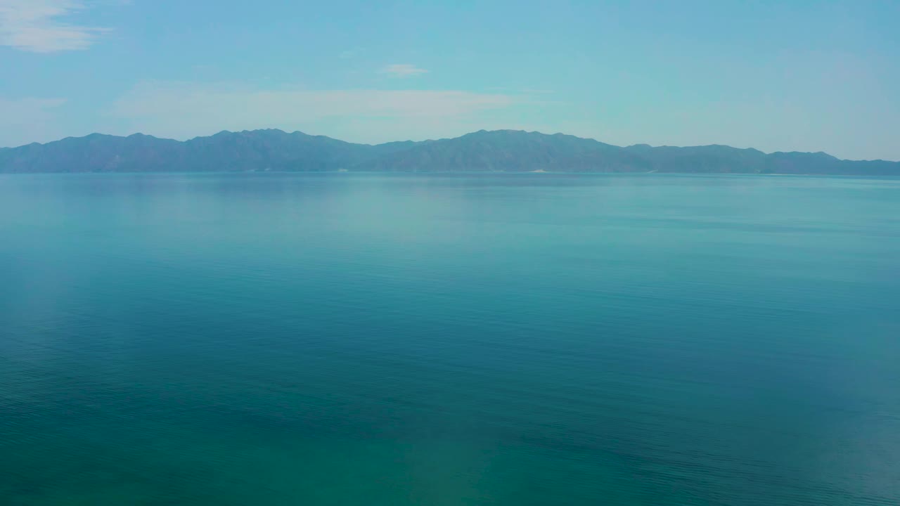 Calm water fills most of the frame with the El Sargento La Ventana mountain horizon held high in the image and no visible people.