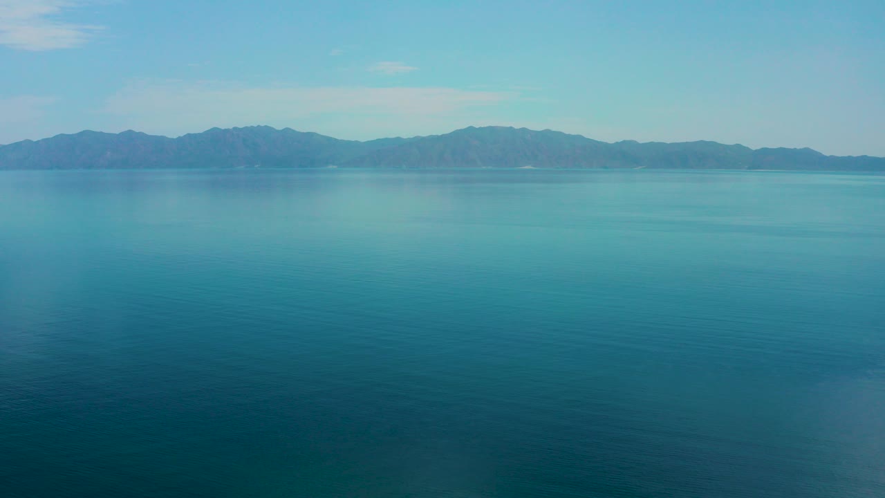 Wide view of blue water and a distant mountain ridge in El Sargento La Ventana, Mexico, with no visible people in the opening frame.