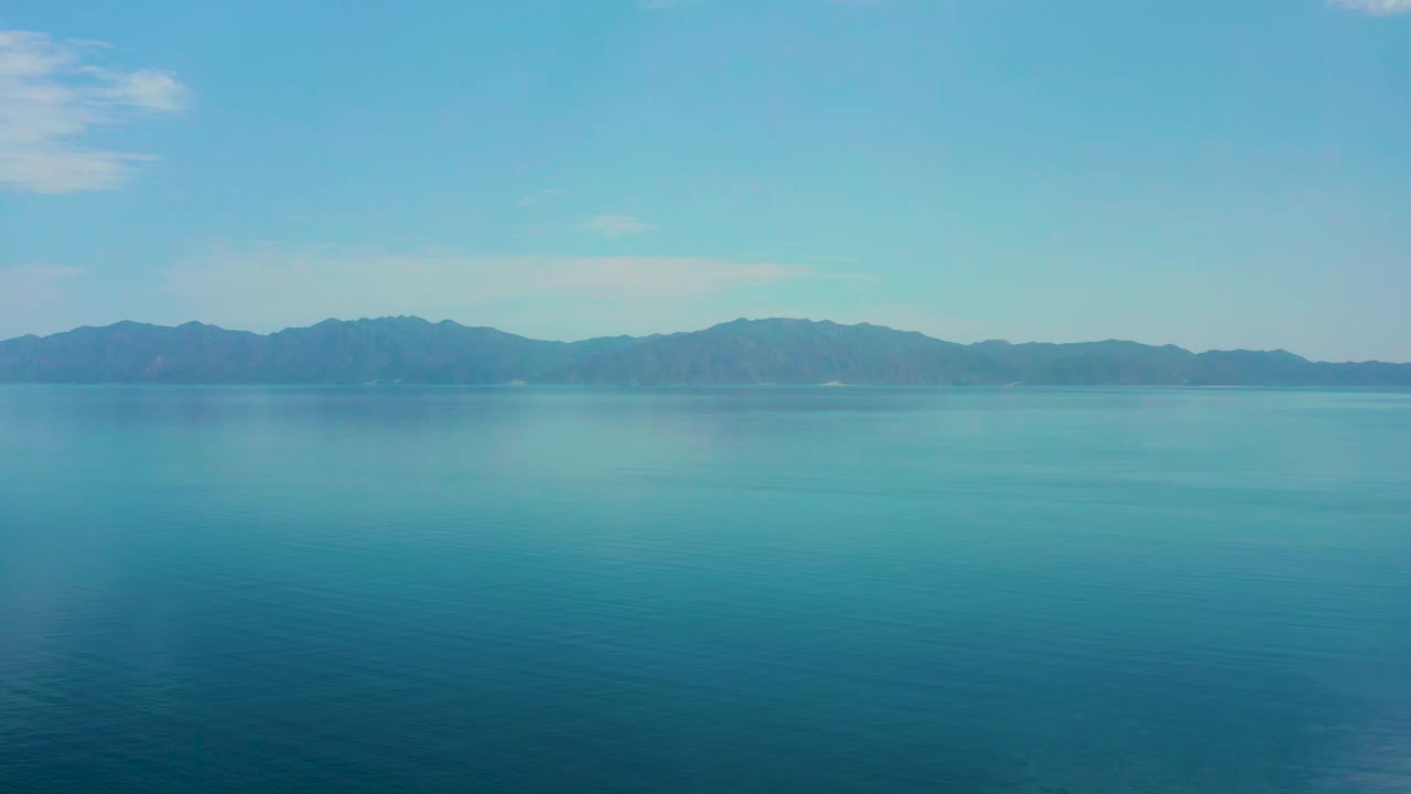 Turquoise water stretching toward a hazy mountain horizon