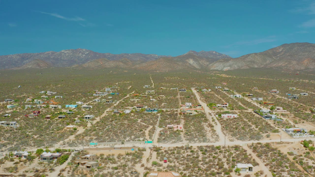 Aerial desert neighborhood with scattered houses and empty roads.