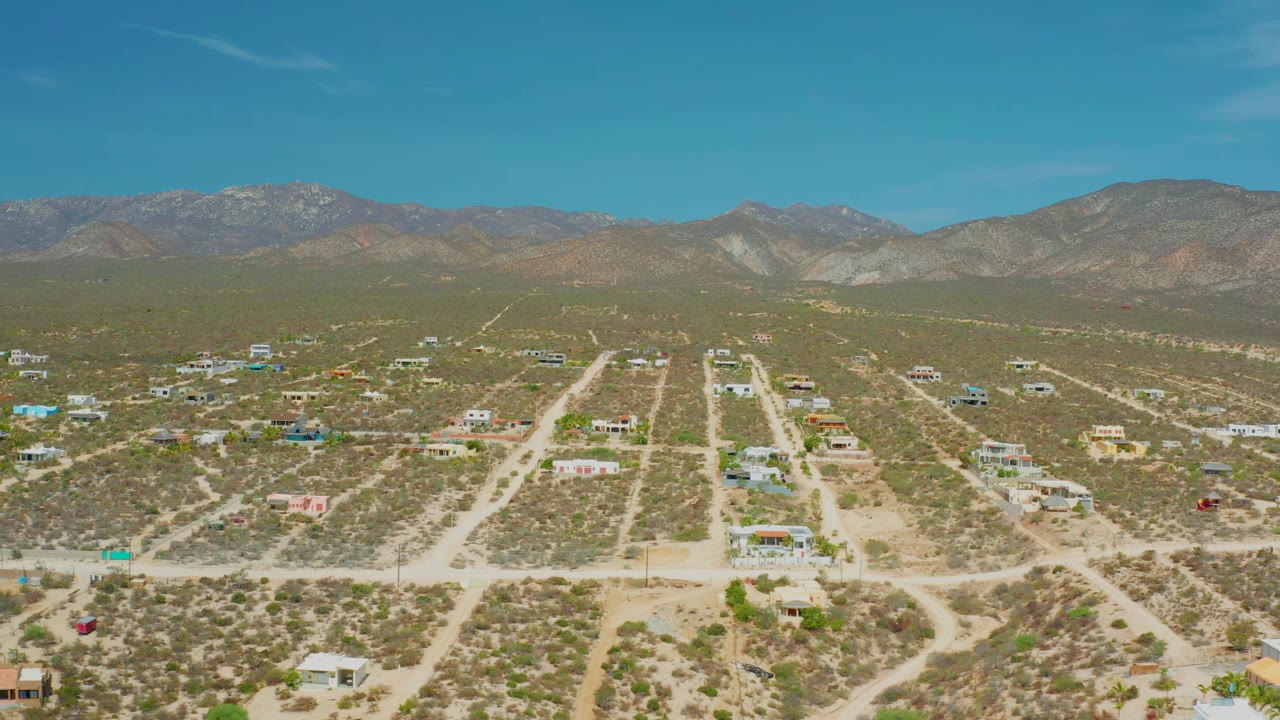 Aerial view of a dry settlement with dirt roads leading toward mountains.