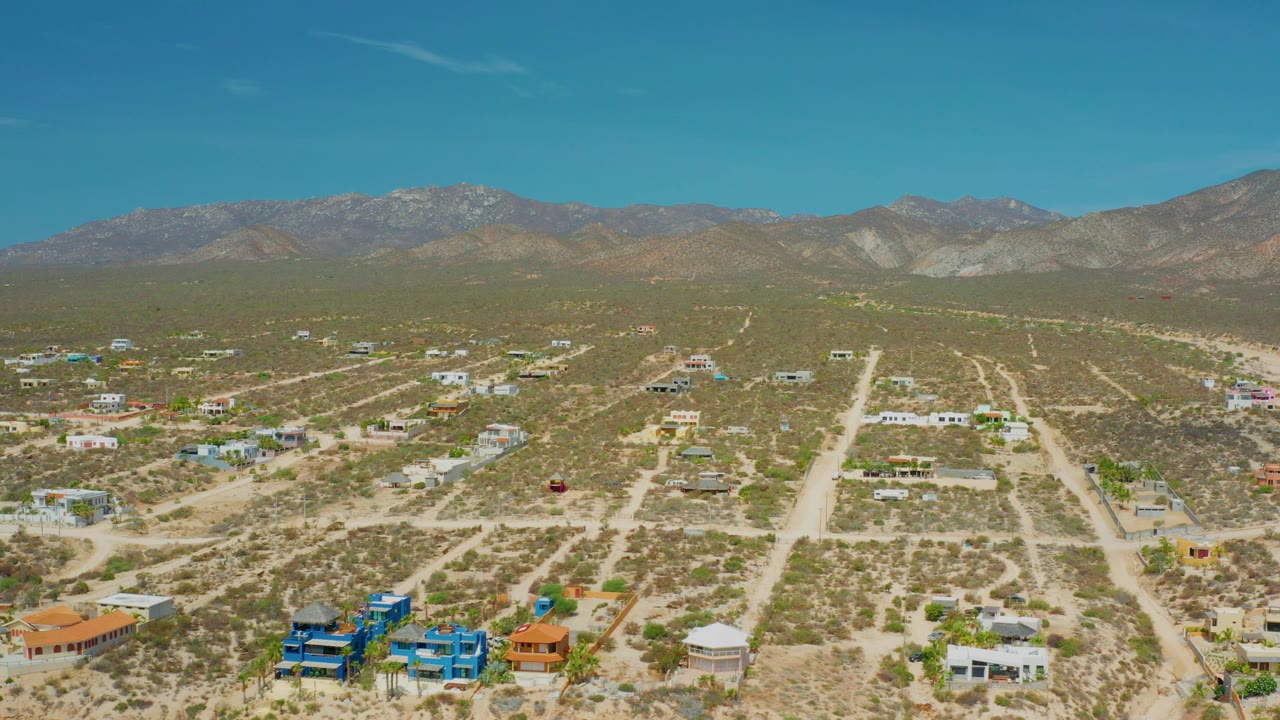 High view of desert homes, road grid, shrubs, and mountain horizon