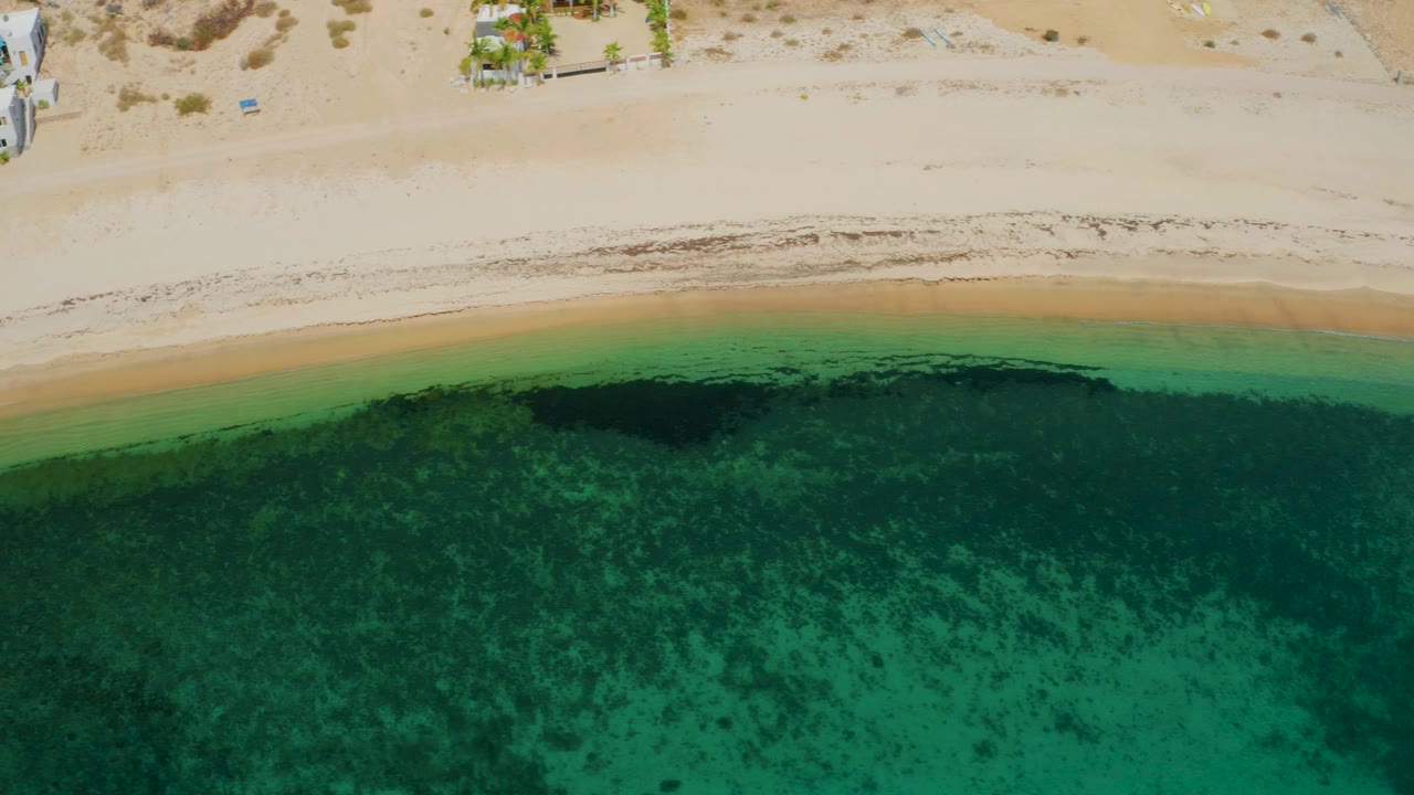 Bright sandy shore above clear green coastal water