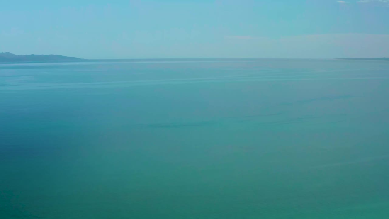 Opening view of blue water and clear sky near El Sargento La Ventana, Mexico, with distant mountains faint on the horizon and no visible people.