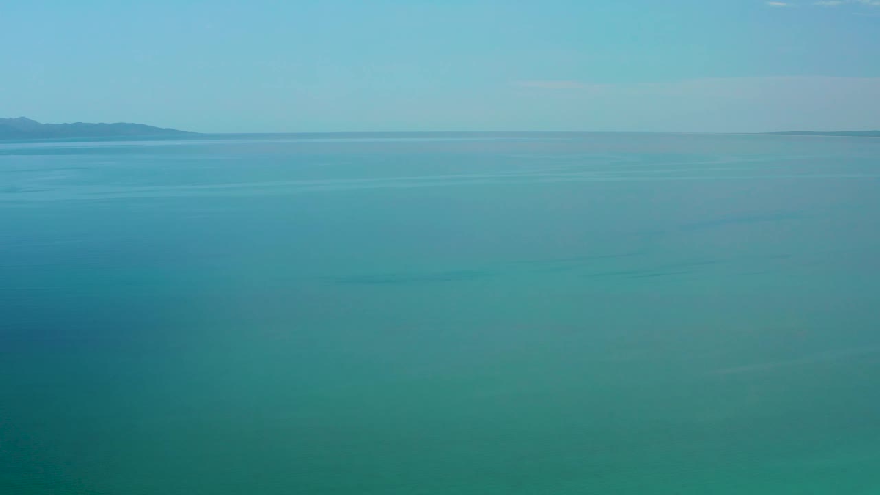 Mid-clip frame of calm blue sea near El Sargento La Ventana, Mexico, with distant mountains running across the horizon and no visible people.