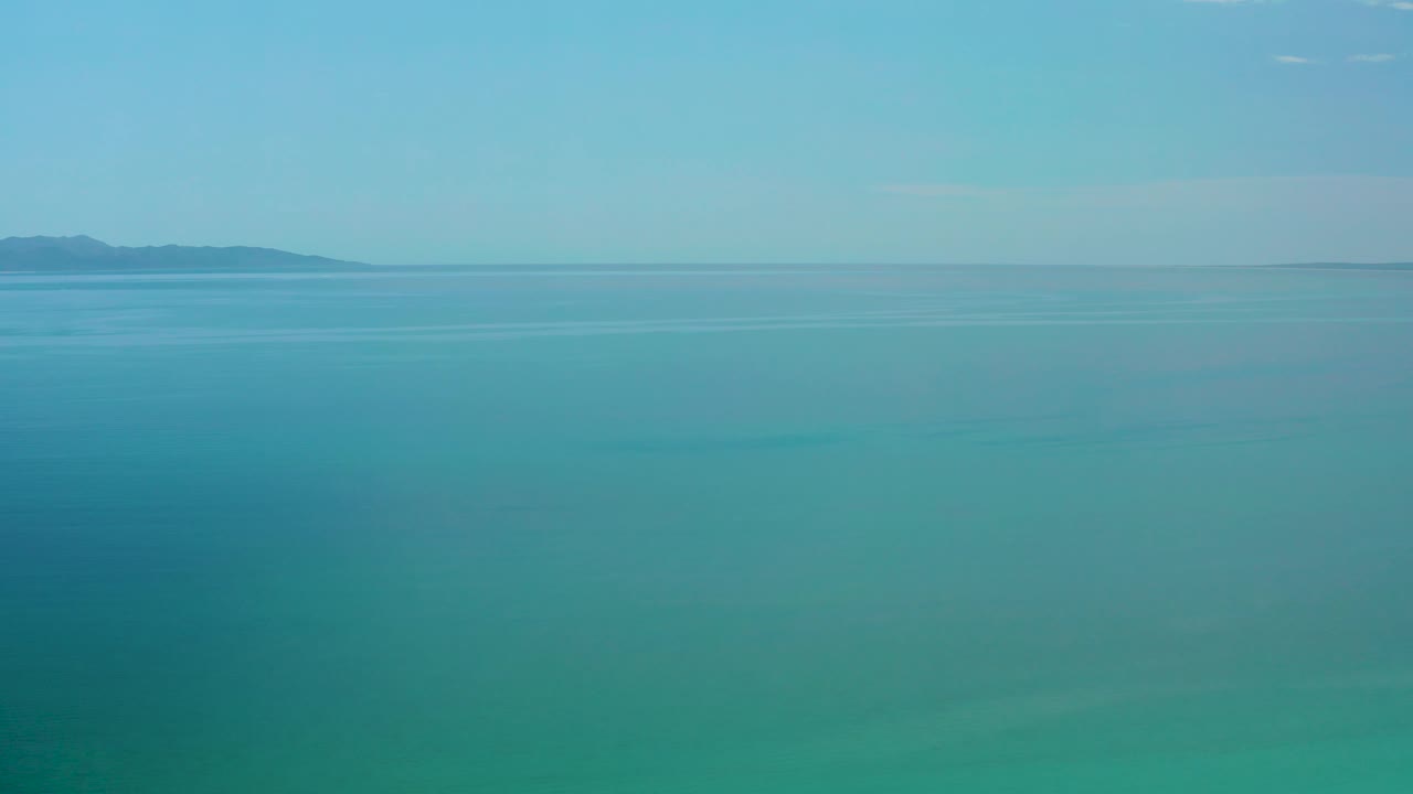 A wide clear sea view in El Sargento La Ventana, Mexico, shows the distant land mass shifted toward the left horizon, soft light on the water, and no visible people.