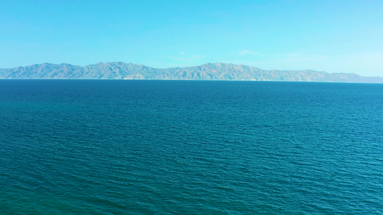 Blue water below distant hills and pale sky