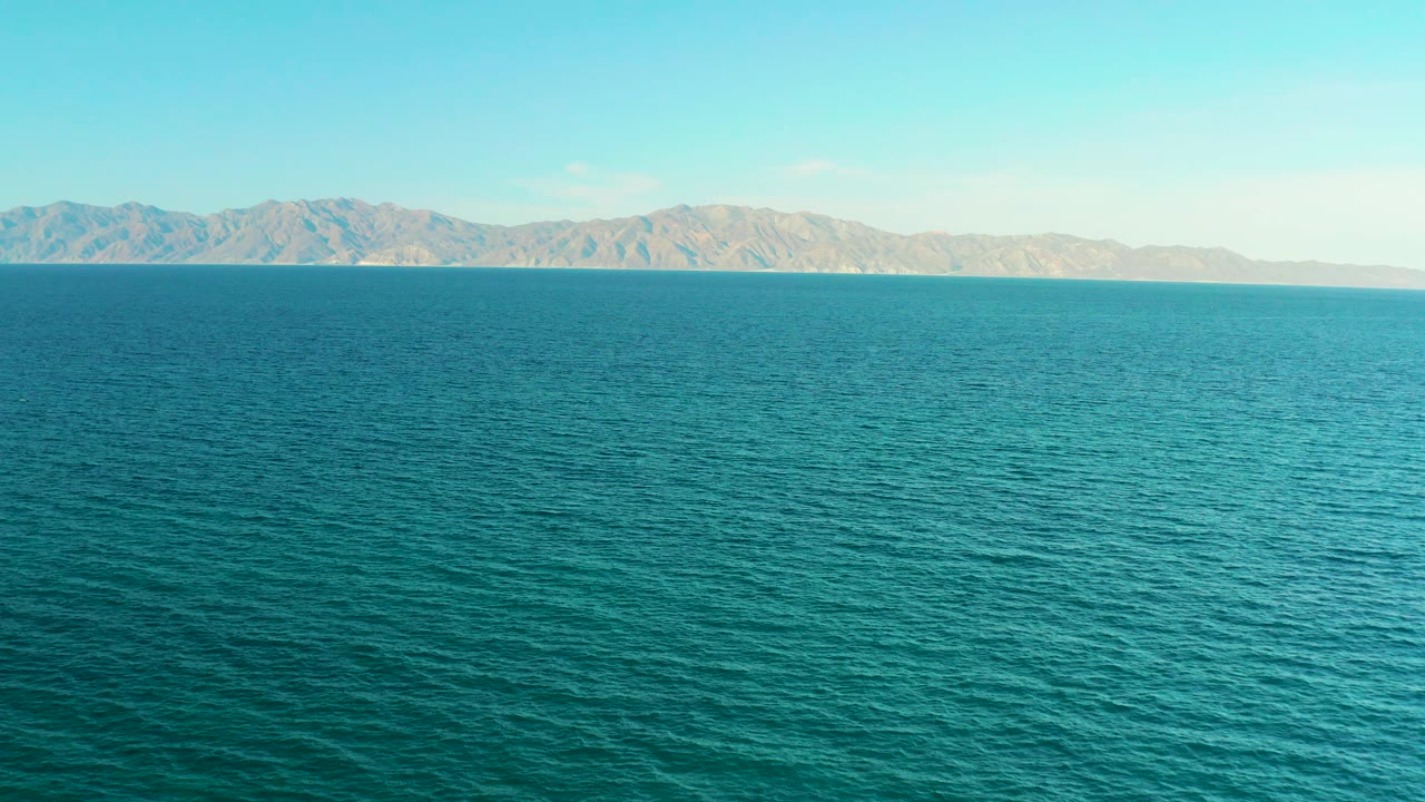 Opening frame of blue ocean in El Sargento La Ventana, Mexico, with a low mountain range on the horizon and no visible people.