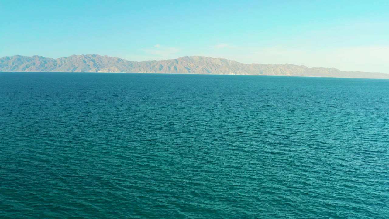 Second frame shows turquoise ocean surface in El Sargento La Ventana, Mexico, with the mountain ridge held across the upper horizon and no visible people.