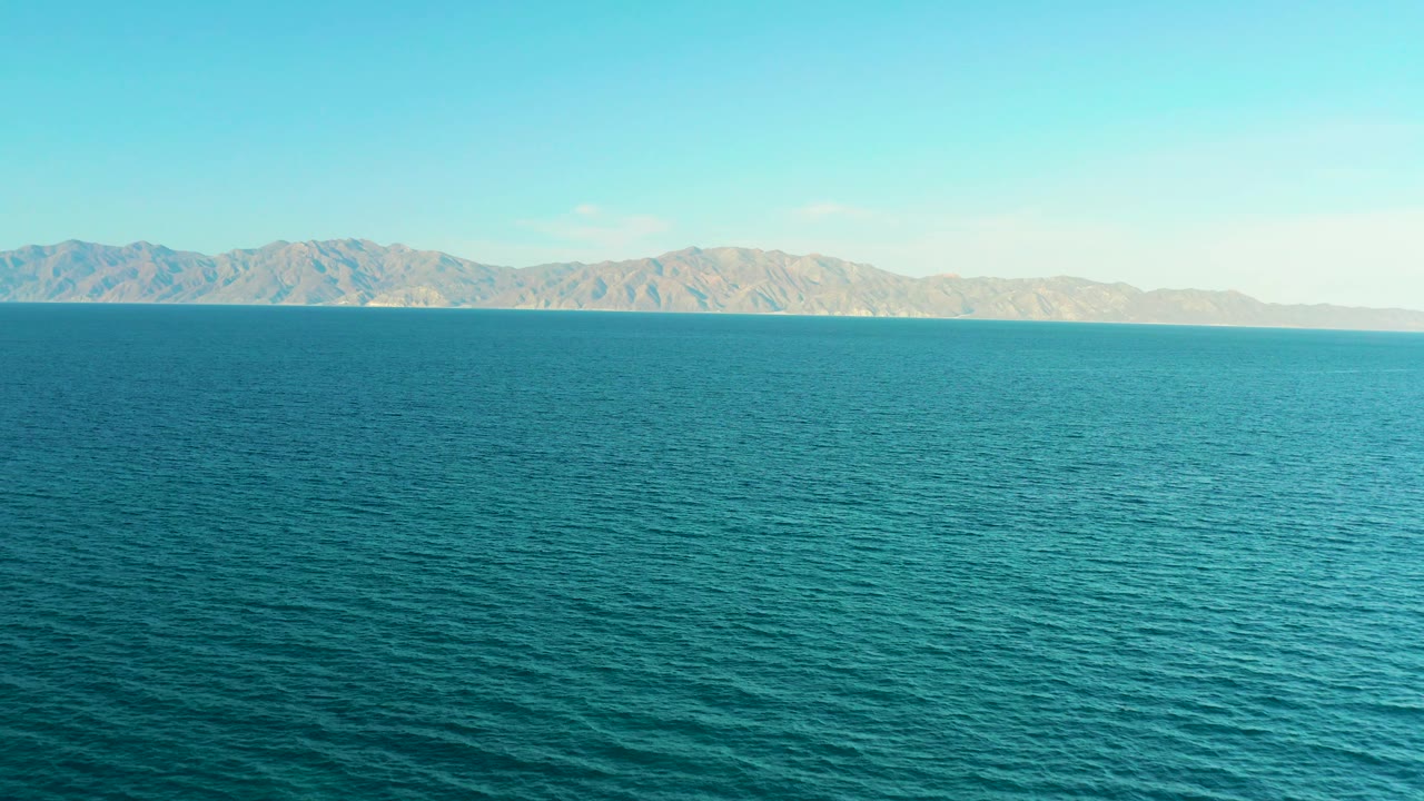 Open blue sea sits below a pale mountain horizon in El Sargento La Ventana, Mexico, with bright sky above and no visible people.