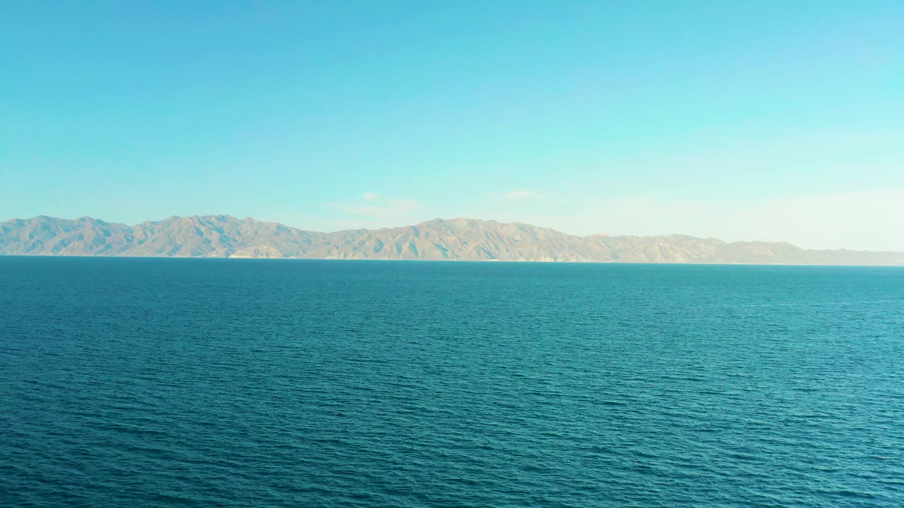 Wide view of rippled blue water and a pale mountain shoreline near El Sargento La Ventana, Mexico, with no visible people.