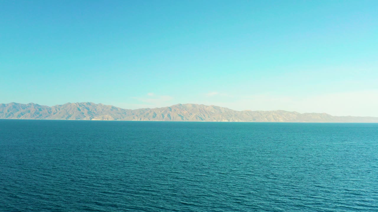 Wide turquoise ocean with distant mountains and blue sky.