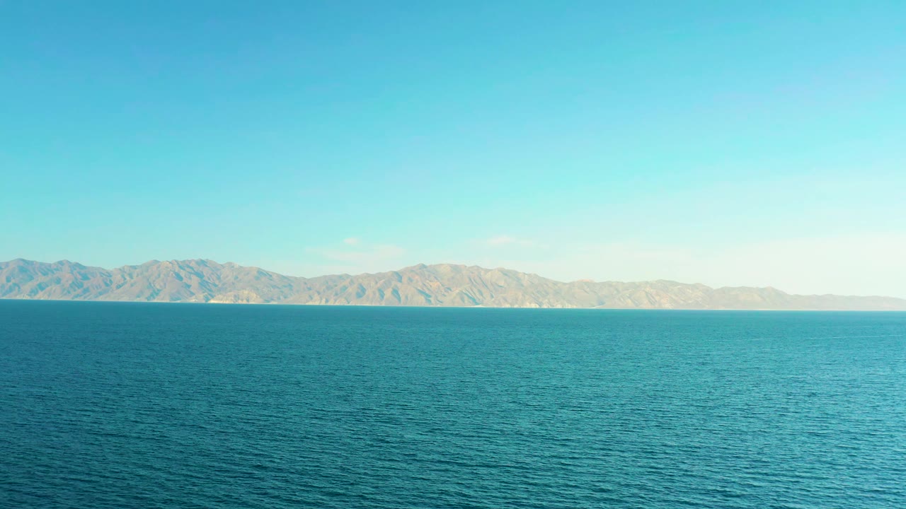 Turquoise water fills the foreground while tan hills sit across the horizon in El Sargento La Ventana, Mexico, with no visible people.