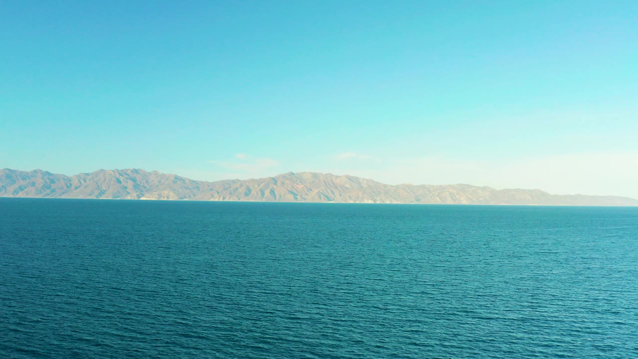 Opening frame of open blue water in El Sargento La Ventana, Mexico, with tan mountains along the horizon and no visible people.