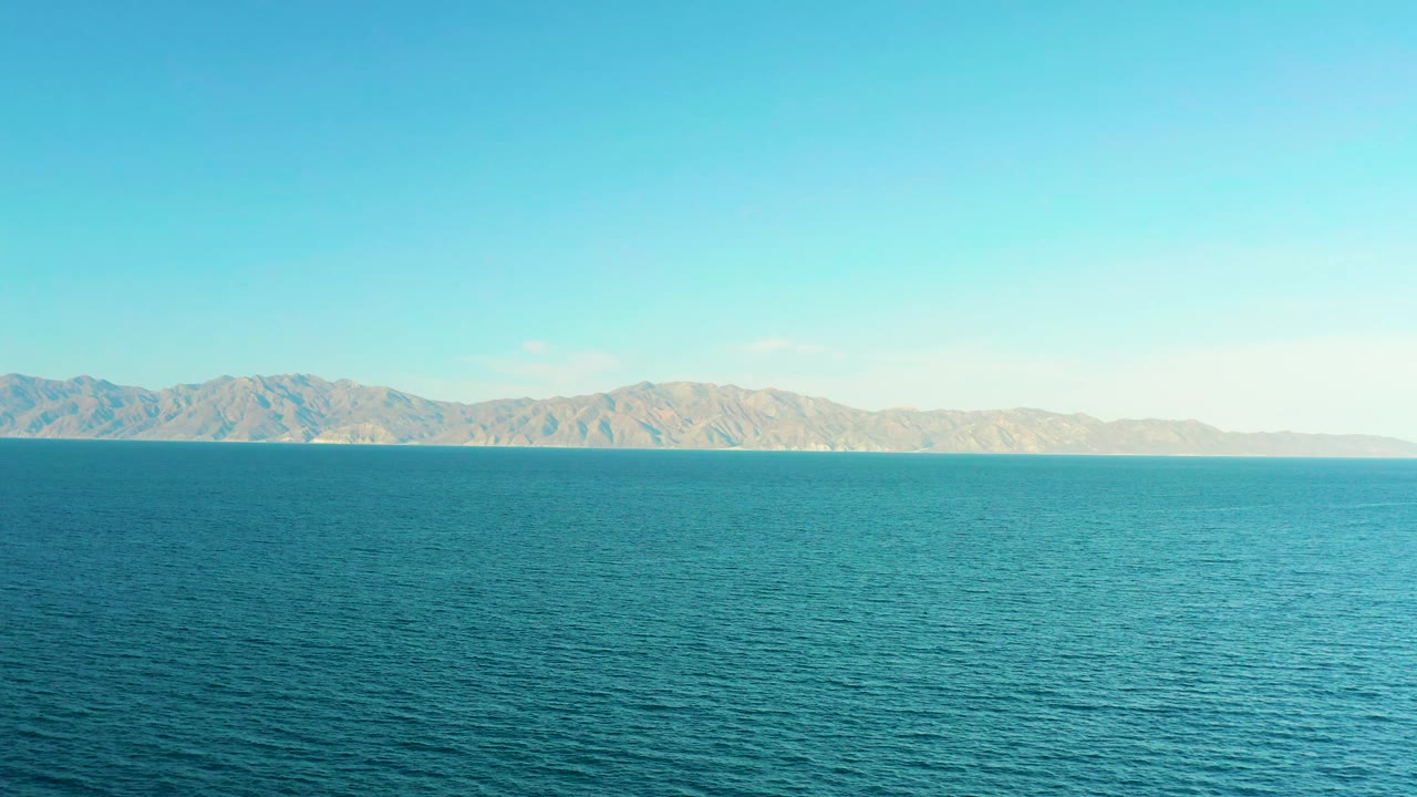 Turquoise water stretches toward a low mountain horizon.