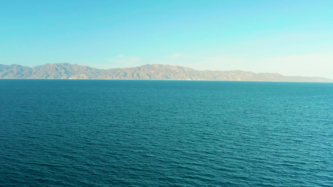 The frame shows textured blue water below a distant mountain coastline in El Sargento La Ventana, Mexico, with the horizon placed near the upper third and no visible people.