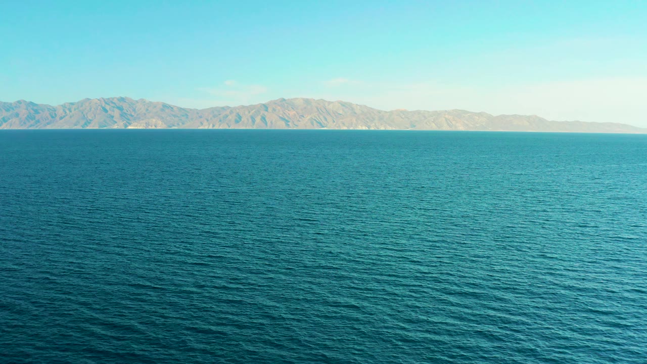 Open water foreground with rugged shoreline across the horizon