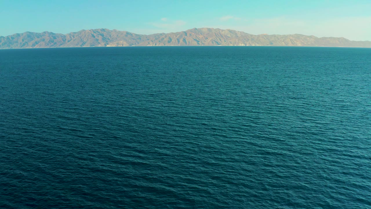 At 0:03, small ripples cover the ocean foreground while the far mountain skyline remains clear in El Sargento La Ventana, Mexico, with no visible people.