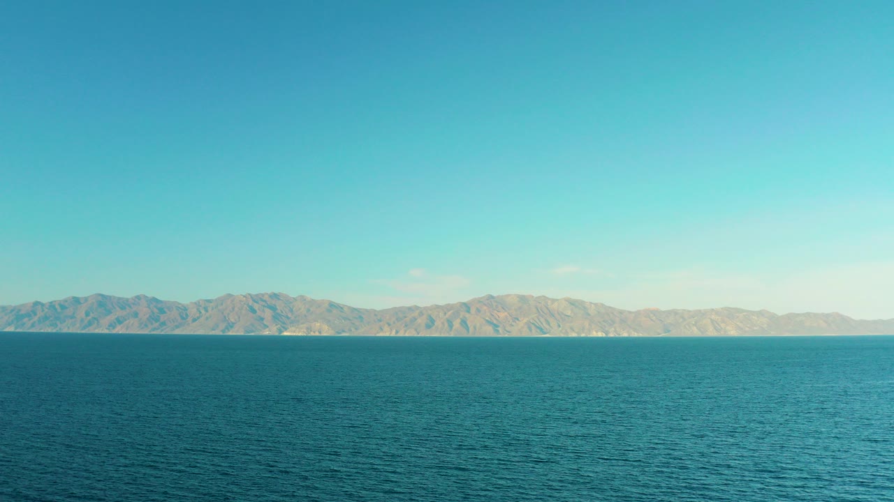Opening frame of teal rippling water and a distant mountain range in El Sargento La Ventana, Mexico, with no visible people.