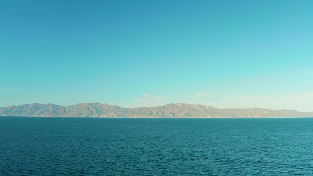 At two seconds, small ripples texture the water surface below arid-looking distant mountains and a clear sky in El Sargento La Ventana, Mexico, with no visible people.