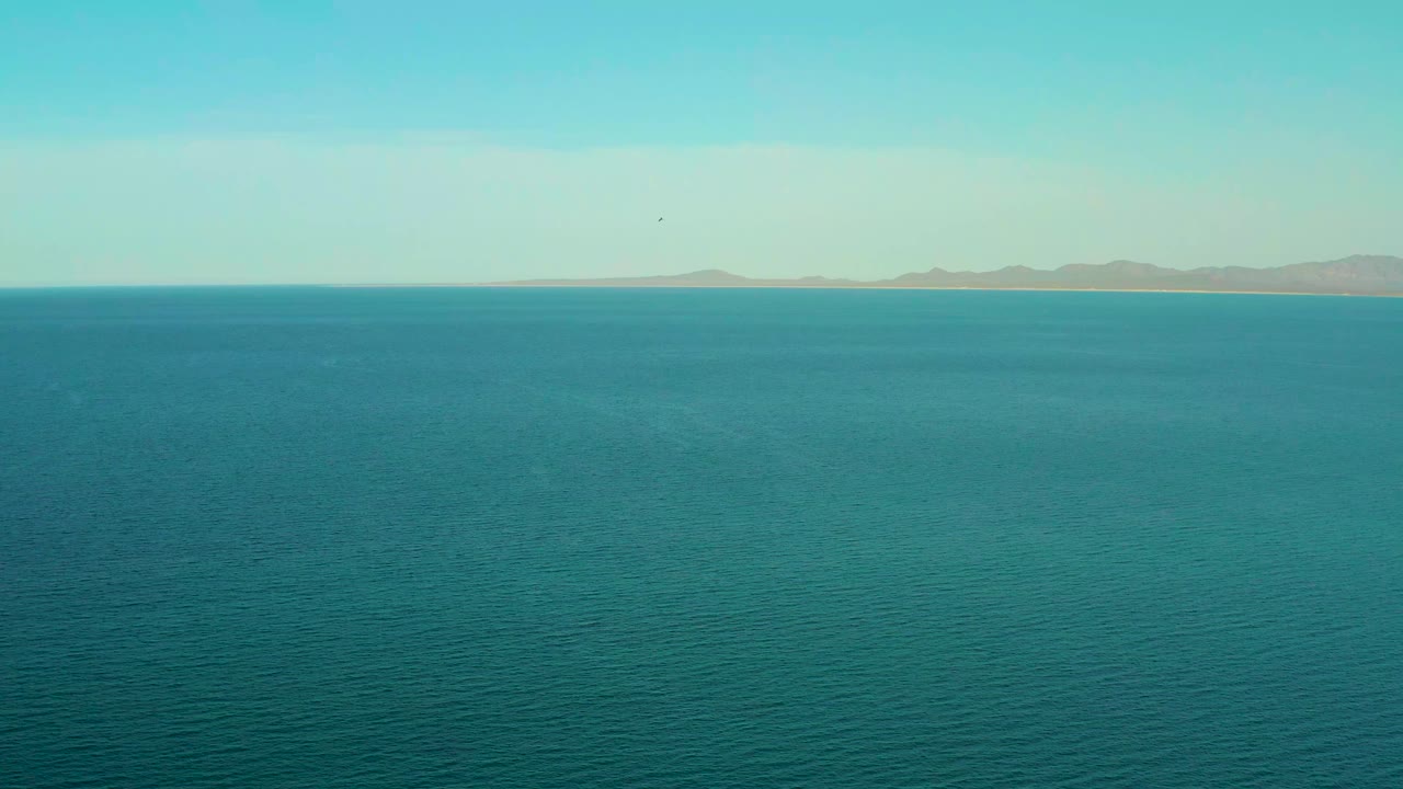 Wide view over blue water toward distant mountains in El Sargento La Ventana, Mexico, with no visible people.