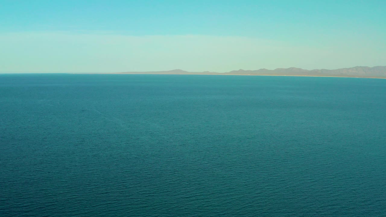 Wide blue ocean with distant coastline and low mountains