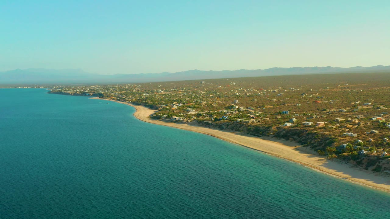 Wide sea foreground with sandy shoreline and inland settlement