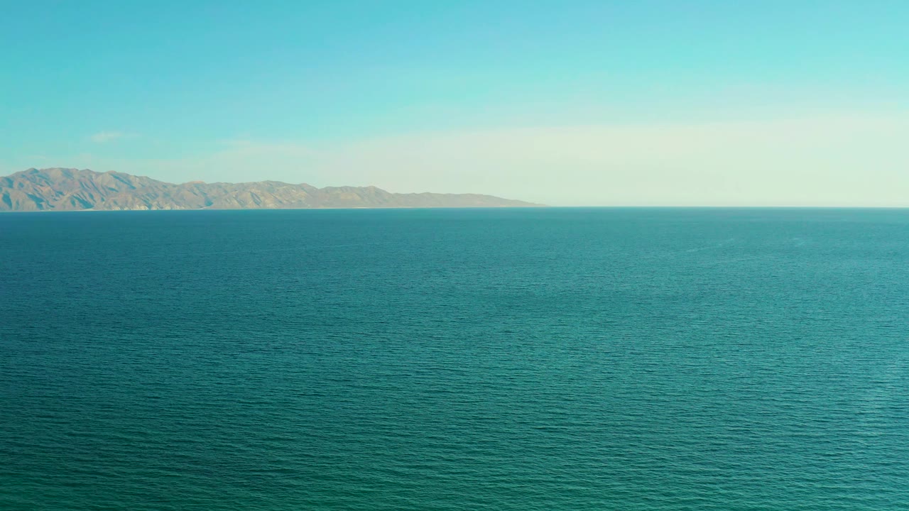 Wide blue-green sea view in El Sargento La Ventana, Mexico, with the mountain ridge slightly more centered and no visible people.