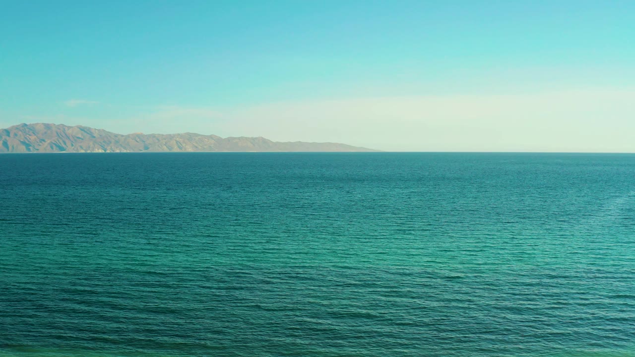 A low mountain coastline sits beyond broad blue water, with no boats, buildings, or visible people interrupting the El Sargento La Ventana view.
