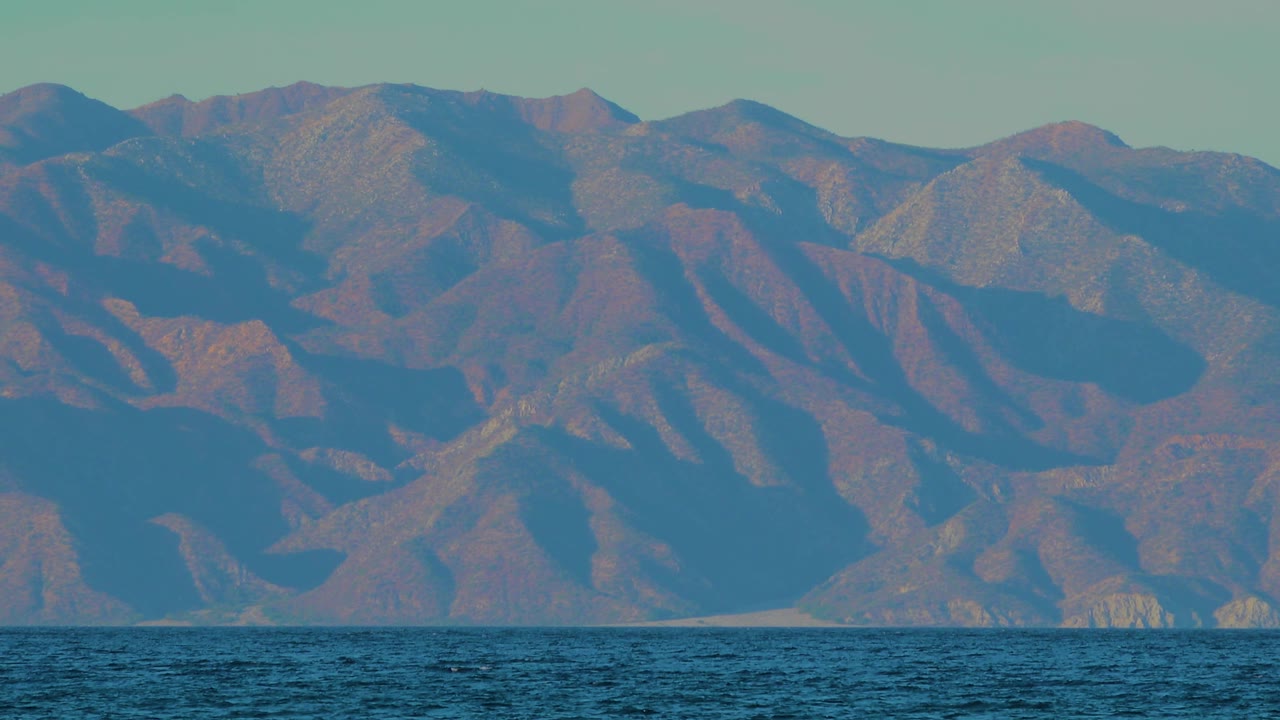 Second frame holds on the rugged mountain ridges beyond a narrow band of ocean water in El Sargento La Ventana, Mexico, with no visible people.